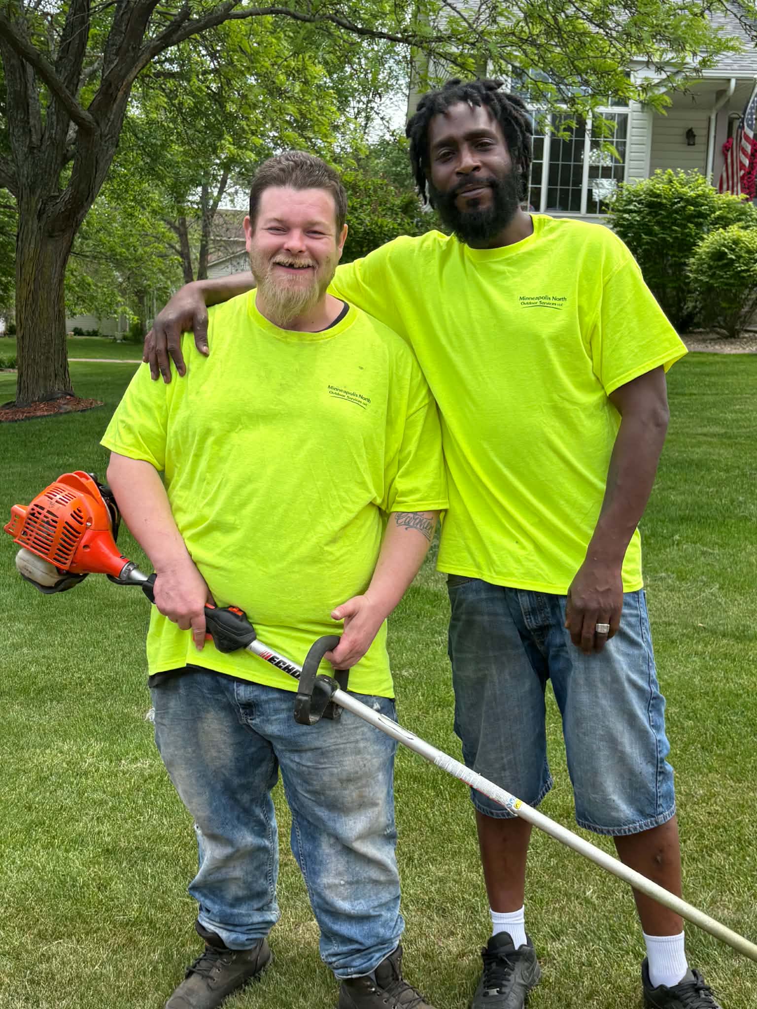 Minneapolis North Outdoor Services crew members Shawn and Dom on a lawn with outdoor service equipment
